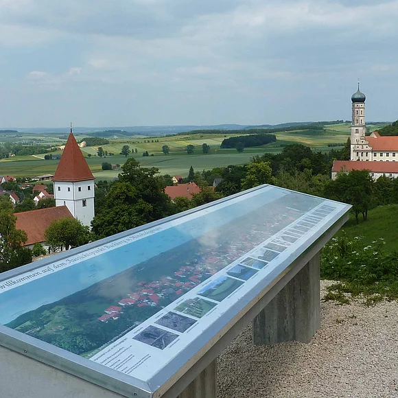 Aussichtspunkt mit Infotafel am Geotop Kühstein in Mönchsdeggingen mit Blick ins Ries. Rechter Hand liegt das ehemalige Kloster bzw. die katholische Pfarrkirche St. Martin. Links die evangelische Pfarrkirche St. Georg.