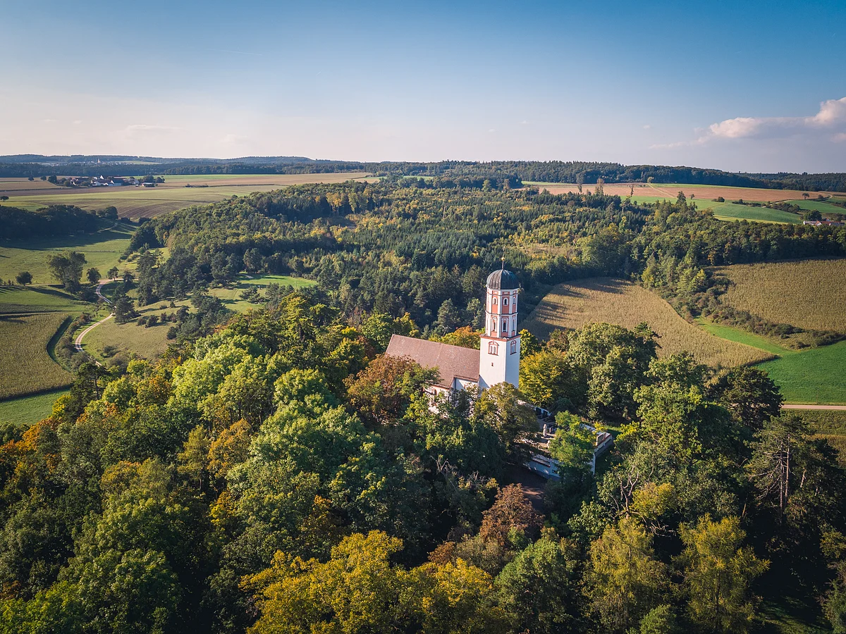 Luftaufnahme des bewaldeten Michelsbergs mit der darauf thronenden Kirche St. Michael.