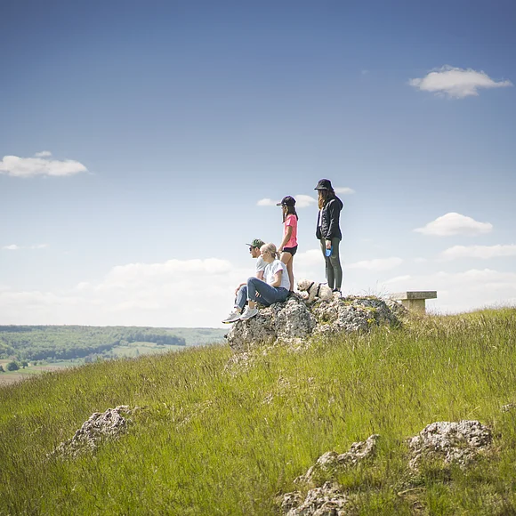 Familie mit Hund sitzen auf dem Bubenheimer Berg auf einem Felsen. Kinder stehen hinter den Eltern Familie mit Hund sitzen auf dem Bubenheimer Berg auf einem Felsen. Kinder stehen hinter den Eltern