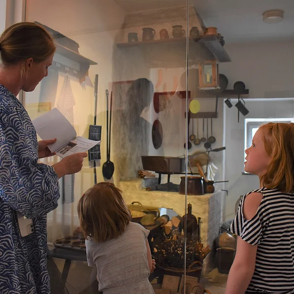 Eine Frau mit zwei Kindern sieht sich die alte Küche im Heimatmuseum an.