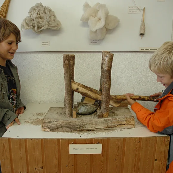 Zwei Jungen probieren das Model einer Steinsäge im Goldbergmuseum aus.