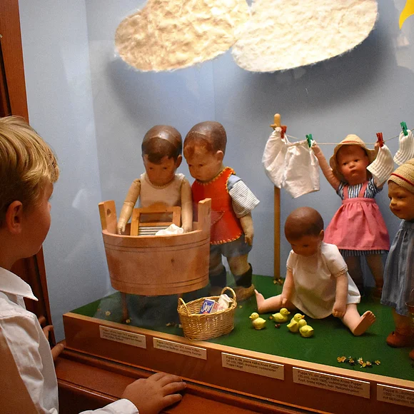 Ein Junge betrachtet eine Puppenszene im Käthe Kruse Puppenmuseum.