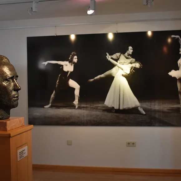 Eine Büste von Werner Egk und Ballett-Bilder an der Wand