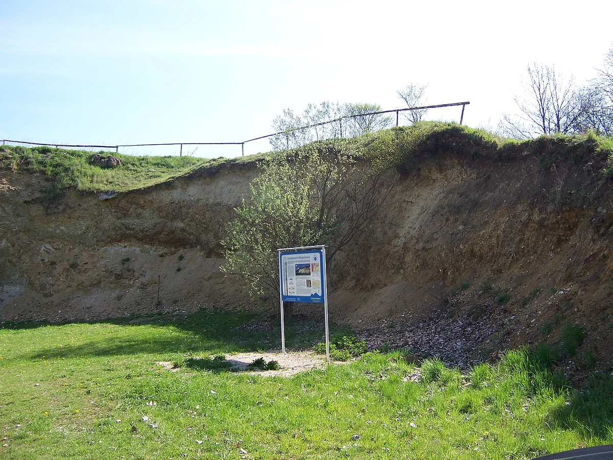 Vor einem steilen, felsigen Hanganriss steht eine Informationstafel.