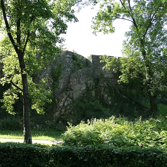 An einen großen Felsblock schließen sich die Mauern einer ehemaligen Burg an.
