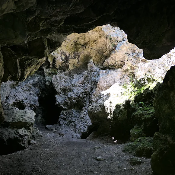 In eine felsige Höhle fällt von oben Licht herein.