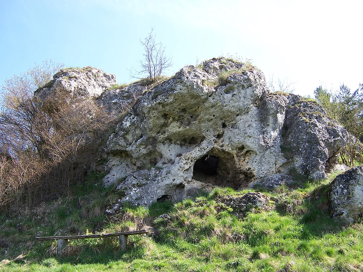Die Kuppe eines Hügels wird von einer Felsformation mit vielen Löchern und Mulden gebildet.