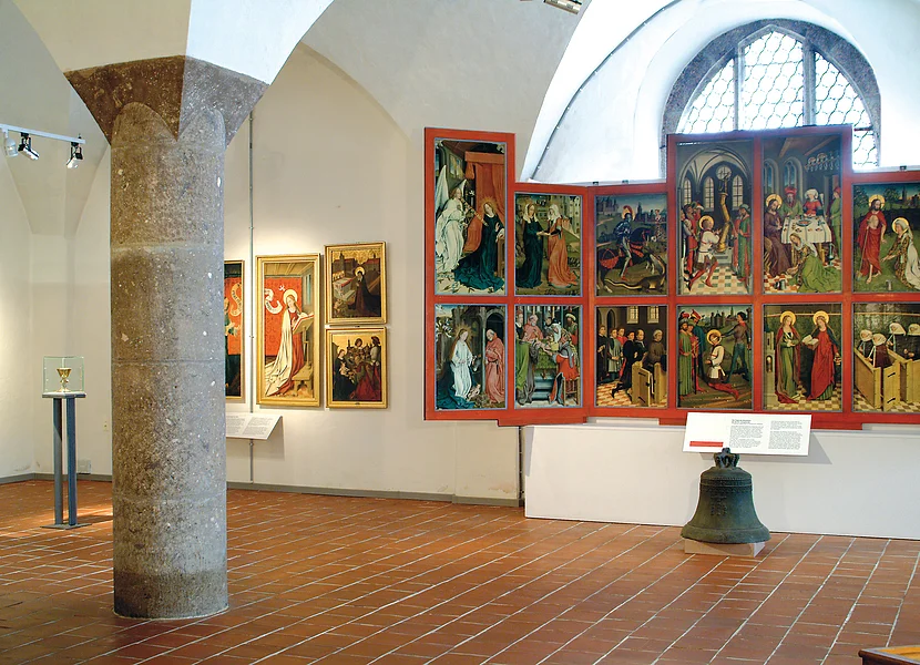 Die Säule eines Gewölbes ist aus dem Gestein Suevit gefertigt. An den Wänden sind geistliche Malereien ausgestellt.