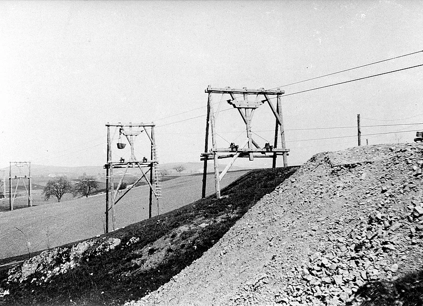 Die schwarz-weiß-Aufnahme zeigt die Holzgerüste einer Drahtseilbahn zum Transport von Gestein.