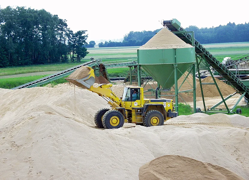 In einer Sandgrube befinden sich mehrere Förderbänder und ein Radlader.