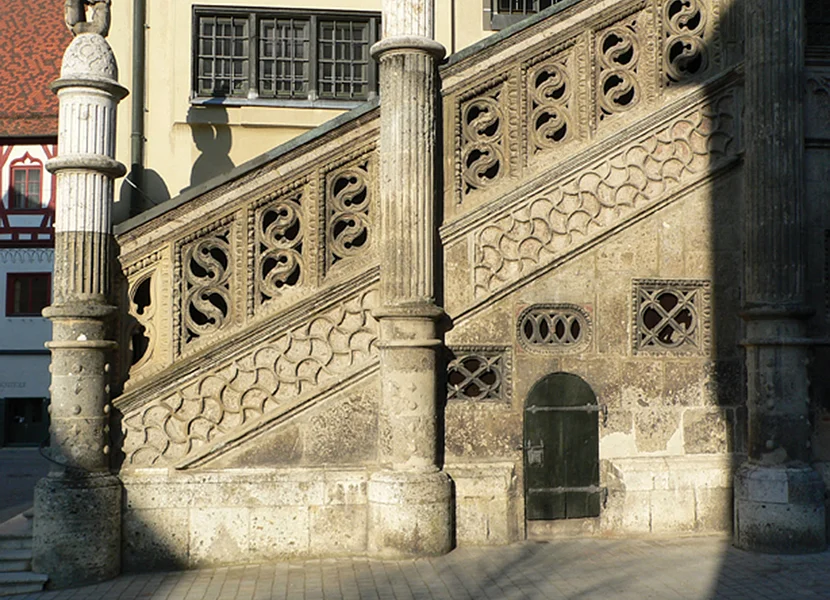 Die Freitreppe vor einem Gebäude ist aus dem Gestein Suevit gefertigt. Unterhalb des Geländers befinden sich kunstvolle Verzierungen.