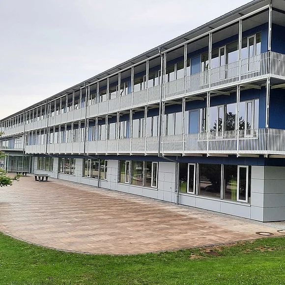 Seitliche Frontansicht der Grund- und Mittelschule Oettingen. Links im Bild ist ein Busch.