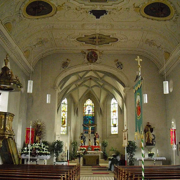 Blick auf den mit Blumen geschmückten Innenbereich mit dem Hauptaltar, zwei Seitenaltären und der Kanzel links im Bild.