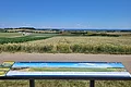 Panoramatafel am Geotop Sandgrube "Am Limberg" mit Blick ins Ries. Hinter der Tafel ist eine kleine Straße.